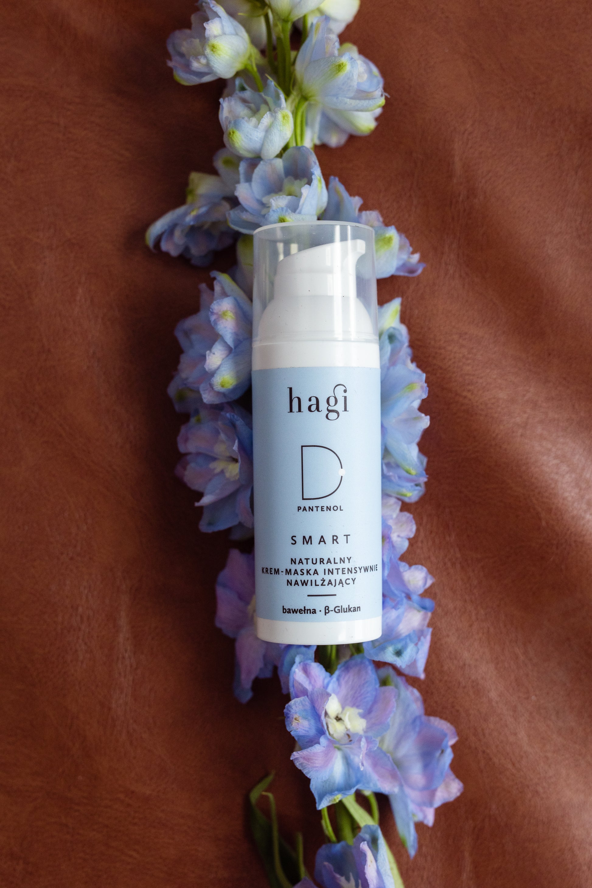 Hagi SMART D Krem-Maska Intensywnie Nawilżająca 50 ml, który leży na kwiecie symbolizującym naturalny skład produktu